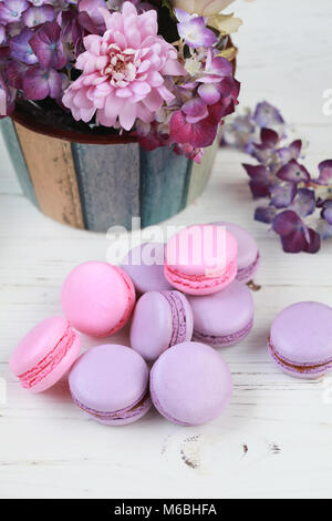 Macaron macaron ou blanc sur fond de bois colorés, biscuits aux amandes avec différentes fleurs et de remplissage. Selective focus Banque D'Images