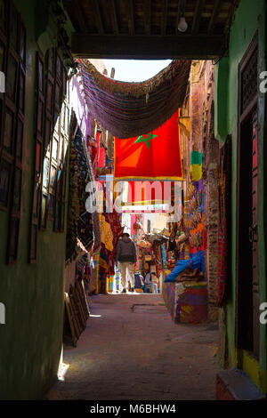 Dans la rue des souks avec des stands, des magasins et des tapis suspendu dans l'ancienne médina de Fes, Maroc Banque D'Images