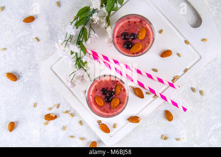 Des smoothies de fruits des bleuets, bananes et amandes dans des verres à cocktail avec tubes sur une planche de bois blanc Banque D'Images