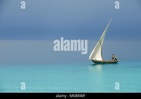 Zanzibar, Tanzanie - 8 novembre, 2016 : Deux pêcheurs navigation un bateau en bois à travers l'océan Indien près de la côte de Zanzibar. Banque D'Images