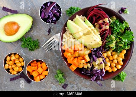 Bol Bouddha avec le quinoa, l'avocat, les pois chiches, les légumes sur une pierre sombre arrière-plan, la saine alimentation concept. Scène de frais généraux. Banque D'Images