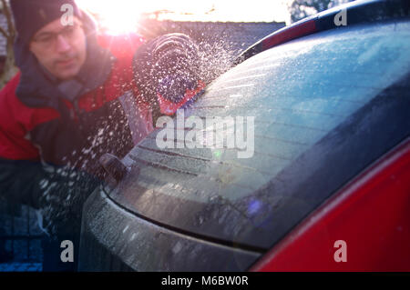 Nettoyage voiture de l'homme et la neige gelée blanche. Le dégivrage du véhicule en hiver. Banque D'Images