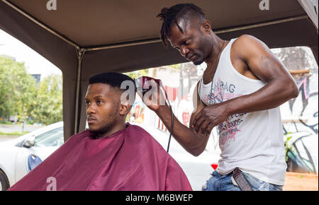 Coupe de cheveux homme dans une boutique de coiffeur à Johannesburg. Banque D'Images