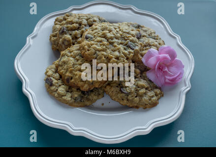 Gros plan sur pile de biscuits et de chocolat en plaque blanche sur fond bleu et décoré avec des fleurs rose- cookies pour maman sur les mères da Banque D'Images