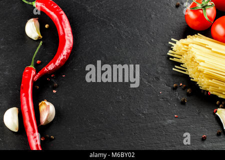 La cuisine italienne. Les légumes, les épices et les pâtes sur fond sombre.Vue de dessus, copiez l'espace. Banque D'Images