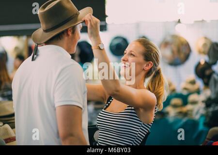 Jeune couple explorent marché Queen Victoria en Australie. La femme est de mettre un chapeau sur son petit ami dans une échoppe de marché. Banque D'Images
