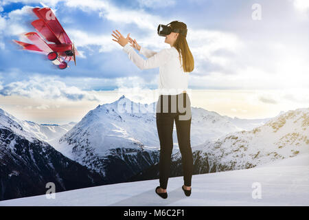 Vol d'un avion près de jeune femme portant des lunettes de réalité virtuelle en temps de neige Banque D'Images