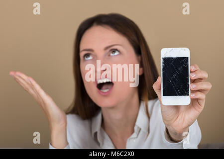 Close-up of Woman Holding malheureux Smart Phone avec écran fissuré Banque D'Images