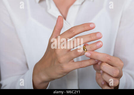 Close-up of a Woman Putting sur un anneau d'or brillant sur le doigt Banque D'Images