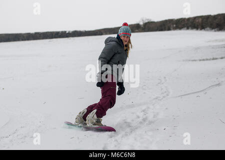 Une femelle snowboarder tire le meilleur de Solsbury Hill conditions sur près de Bath après de fortes chutes de neige. Bête de l'Est, tempête Emma Banque D'Images