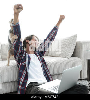 Heureux guy jubile avec son chien assis près du canapé dans le salon. Banque D'Images
