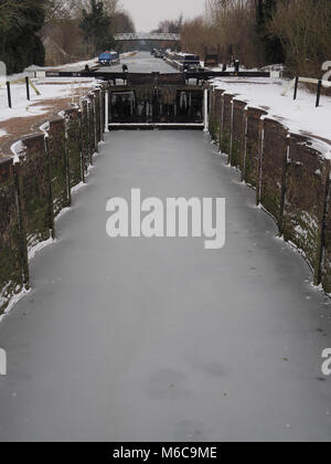 Hiver neige et glace dans le bas de la serrure d'Aldermaston historique avec les glaçons sur des portes de l'écluse et le canal et la passerelle des bateaux dans la distanc Banque D'Images