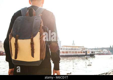 Un jeune homme touriste avec un sac à dos se trouve à côté de la rivière Vltava à Prague et admire le bateau de passage. Voyage autour de la République tchèque. Sites touristiques. Banque D'Images