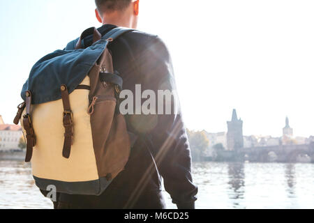 Un jeune homme touriste avec un sac à dos se trouve à côté de la rivière Vltava à Prague et admire l'architecture de la ville. Voyage autour de la République tchèque. Banque D'Images