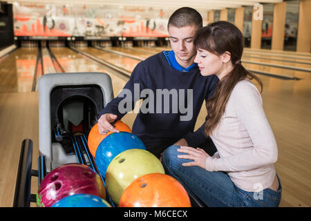 Jeune couple choisissant bowling ball Banque D'Images