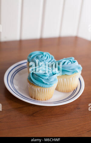 Trio de cupcakes à la vanille avec glaçage bleu sur une plaque Banque D'Images