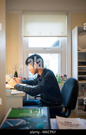 Un jeune étudiant asiatique travaille dans sa chambre pour lire un livre et la révision à la maison Banque D'Images