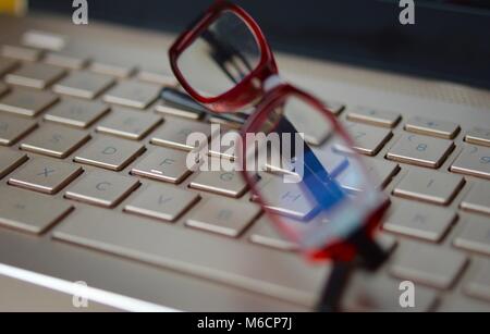 Lunettes fatigué sur un clavier d'ordinateur portable de couleur bronze Banque D'Images