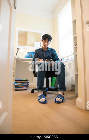 Un jeune étudiant asiatique travaille dans sa chambre pour lire un livre et la révision à la maison Banque D'Images