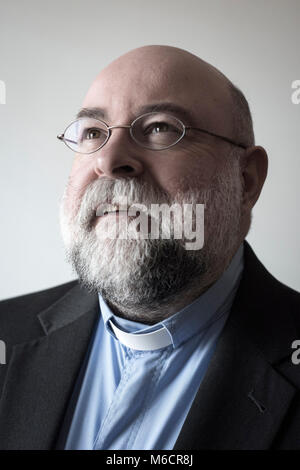 Un vicaire de sexe masculin avec une barbe et lunettes rondes a l'air de l'appareil photo dans un portrait classique posent Banque D'Images