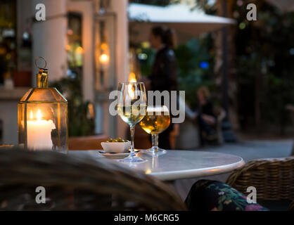 Un verre de vin et de la bière avec des olives sur une table dans un restaurant chaleureux. Banque D'Images