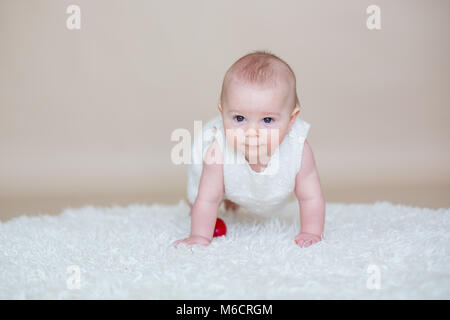 Cute little toddler baby boy, jouant avec les oeufs de Pâques colorés et peu de canards décoratifs, isolé tourné, fond beige Banque D'Images