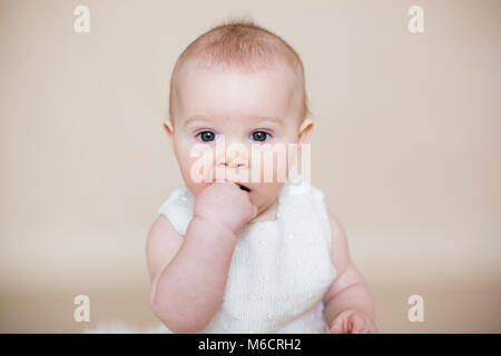 Fermer portrait of cute little baby boy, isolé sur fond beige, des différentes expressions du visage de bébé, pleurer, triste, sourire, rire Banque D'Images