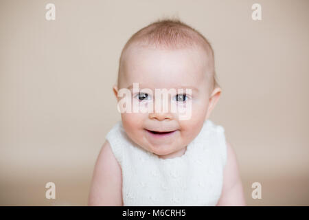 Fermer portrait of cute little baby boy, isolé sur fond beige, des différentes expressions du visage de bébé, pleurer, triste, sourire, rire Banque D'Images