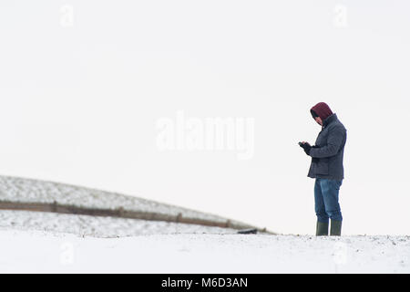 Penarth, au Pays de Galles. 2 mars 2018. Un homme utilise son téléphone à Penarth, près de Cardiff. Storm Emma et 'La Bête de l'Est' ont frappé le Royaume-Uni, avec une alerte rouge pour la neige et le vent émis pour les régions entourant Cardiff, Newport, Pays de Galles du Sud, les vallées et le sud-ouest de l'Angleterre. Photo de Thomas Polly Polly Crédit : Thomas/Alamy Live News Banque D'Images