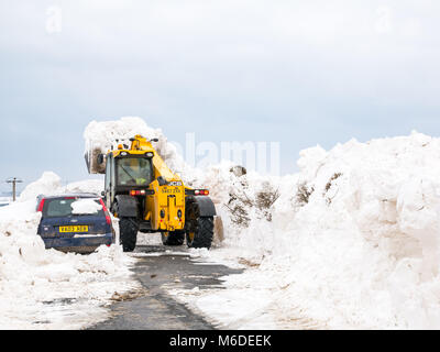 East Lothian, Ecosse, Royaume-Uni, le 3 mars 2018. Météo France : la route locale entre Drem et Haddington est fermé par d'énormes amoncellements de neige après le mauvais temps d'arctique extrême surnommé 'la bête de l'Est'. Conseil d'un creuseur est frayer la voie. Une voiture est enterré dans la neige Banque D'Images