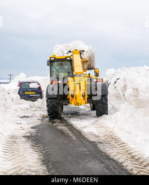 East Lothian, Ecosse, Royaume-Uni, le 3 mars 2018. Météo France : la route locale entre Drem et Haddington est fermé par d'énormes amoncellements de neige après le mauvais temps d'arctique extrême surnommé 'la bête de l'Est'. Conseil d'un creuseur est frayer la voie. Une voiture est enterré dans la neige Banque D'Images