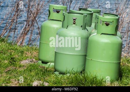 Quatre bouteilles de propane debout sur un champ près de l'eau Banque D'Images