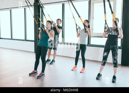 Expert professionnel TRX total body exercices contre résistance formateurs formation tirez ensemble dans la lumineuse salle de classe de la salle de sport. Banque D'Images