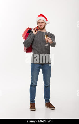 Concept de Noël - beau jeune homme barbe tenant un verre de champagne et des sacs avec des professionnels de l'expression du visage. Banque D'Images