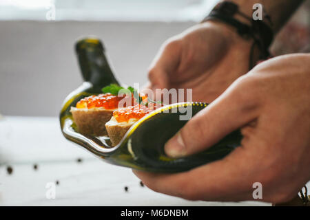 Seulement les mains. L'homme termine son assiette et presque prêt à servir à la table. Libre. Décoration de la table. Plats de service. Manger en belle lave Banque D'Images