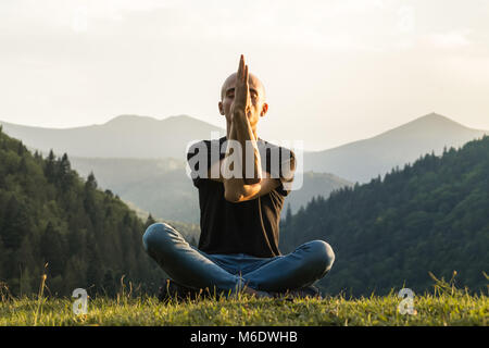 Personne mâle skinny paisiblement assis dans la position du lotus haut de la colline dans les Carpates ukrainiennes Banque D'Images