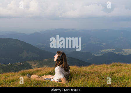 Female hiker en casque avec téléphone cellulaire sur une prairie de montagne Banque D'Images