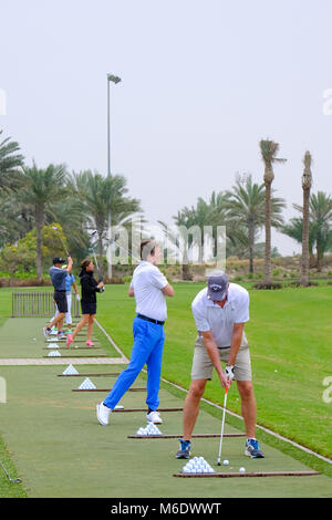 Groupe de joueurs de golf train / pratiquant à Saadiyat Beach Golf Course, Abu Dhabi ÉMIRATS ARABES UNIS. Banque D'Images