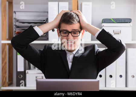 Close-up of a frustré les jeunes Businessman Looking At Laptop Banque D'Images