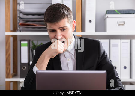 Close-up of a inquiété Businessman Looking At Laptop In Office Banque D'Images
