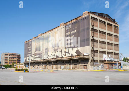 Port du Pirée, Grèce - Mai 30, 2017 : l'un de l'ancien silo et cales sèches bâtiments avec la peinture du mur près de la côte avec ses silos Ietioneias Floa Banque D'Images