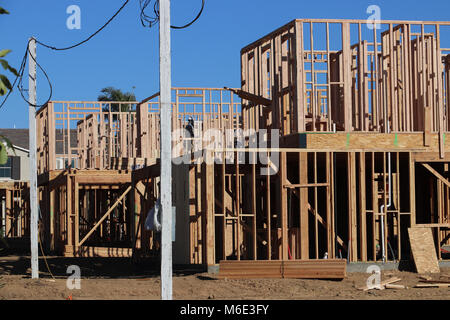 Plusieurs nouvelles maisons de deux étages en construction, à pans, avec murs squelettique construit de bois 2 x 4 ; bleu ciel derrière, poteaux électriques, aux beaux jours. Banque D'Images