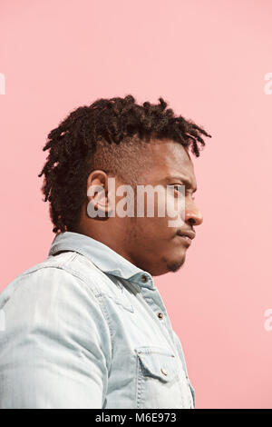 L'homme d'affaires suspectes et permanent Afro suspicieusement à contre fond rose. Vue de profil. Banque D'Images