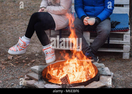 Deux amis sont assis autour d'un feu de camp et relaxant, backpackers se reposer près de camp, l'arrière-plan touristique Banque D'Images