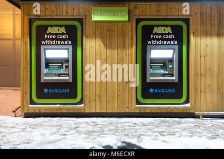 Les distributeurs dans le côté d'un supermarché Asda, exploité par la banque Barclays, photo sur une nuit enneigée. Banque D'Images