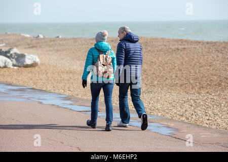 Un couple en train de marcher le long de la mer sur une journée froide. Banque D'Images