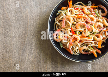 Faire revenir avec les nouilles Udon, crevettes (crevettes) et de légumes. La nourriture saine, de l'Asie, repas sautés au wok sur fond de bois, copie de l'espace. Banque D'Images