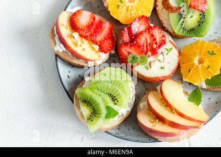 Dessert de fruits des sandwiches à base de ricotta. Délicieux petit déjeuner sain des toasts avec du fromage à la crème, fruits frais biologiques et de baies, herbes, noix et Banque D'Images