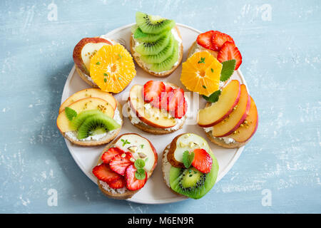 Dessert de fruits des sandwiches à base de ricotta. Délicieux petit déjeuner sain des toasts avec du fromage à la crème, fruits frais biologiques et de baies, herbes, noix et Banque D'Images