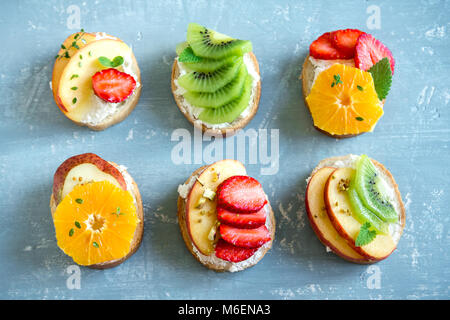 Dessert de fruits des sandwiches à base de ricotta. Délicieux petit déjeuner sain des toasts avec du fromage à la crème, fruits frais biologiques et de baies, herbes, noix et Banque D'Images